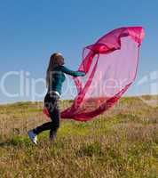 young beautiful woman jumping with tissue into the field against