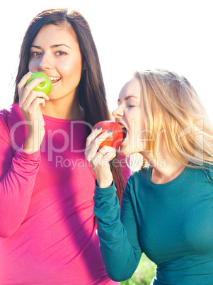 portret of two young beautiful woman with apple on the  sky back