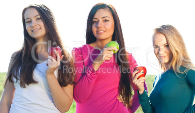 portret of three young beautiful woman with apple on the  sky ba