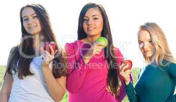 portret of three young beautiful woman with apple on the  sky ba