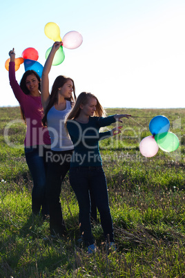 three young beautiful woman with balloons into the field against