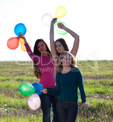 three young beautiful woman with balloons into the field against