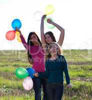 three young beautiful woman with balloons into the field against
