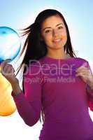 young beautiful woman with balloons into the field against the s