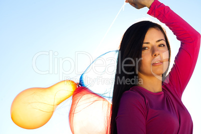 young beautiful woman with balloons into the field against the s