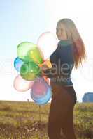 young beautiful woman with balloons into the field against the s