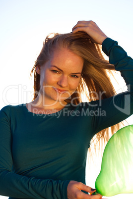 young beautiful woman with balloons into the field against the s