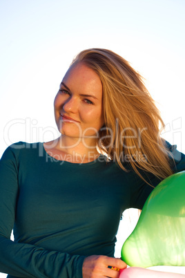 young beautiful woman with balloons into the field against the s