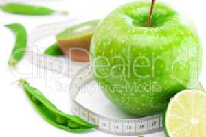 apple,lime,peas,kiwi and measure tape isolated on white