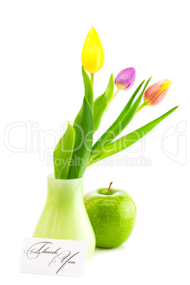 colorful tulips in vase,apple and a card signed thank you isolat