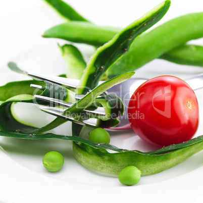 tomato,fork ,cucumber skin,peas and measure tape on a plate isol