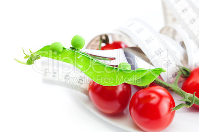 tomato,fork ,peas and measure tape on a plate isolated on white