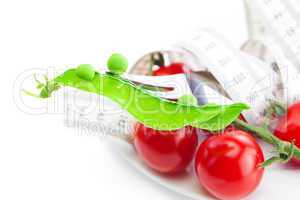 tomato,fork ,peas and measure tape on a plate isolated on white