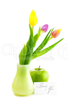 colorful tulips in vase,apple and a card signed thank you isolat