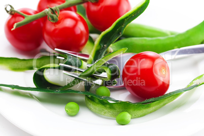 tomato,fork ,cucumber skin,peas and measure tape on a plate isol