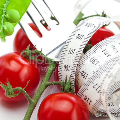 tomato,fork ,peas and measure tape on a plate isolated on white