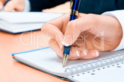 Cropped image of hand of young woman taking notes