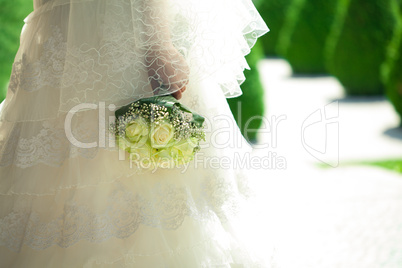 bouquet in the hands of the bride against the background of dres