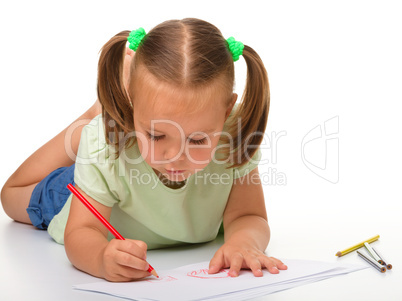 Little girl is drawing while laying on the floor