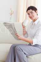 Portrait of a woman with a cup reading the news while looking at