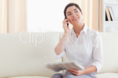 Cheerful Woman with a cellphone and a newspaper