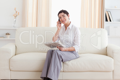 Cute woman with a cellphone and a newspaper