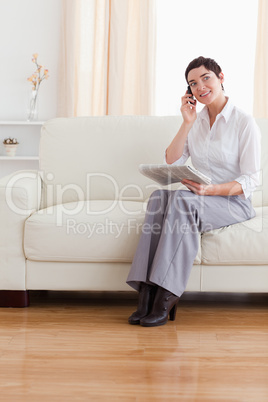 Cute brunette woman with a cellphone and a newspaper