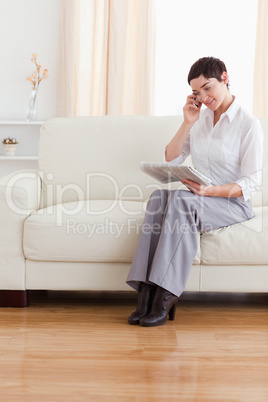 Beautiful woman with a phone and a newspaper