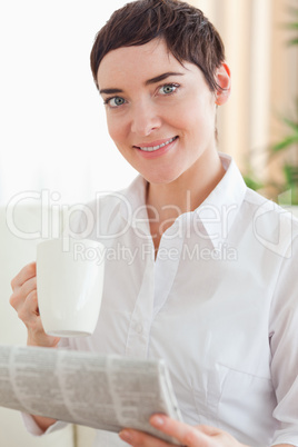 Charming woman with a cup and a newspaper