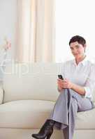 Charming Woman sitting on a sofa with a phone