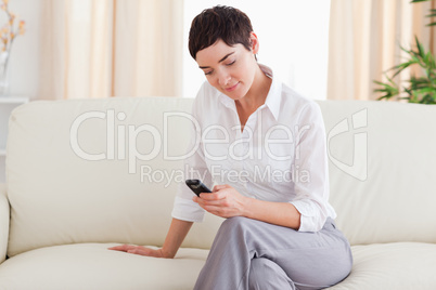 Charming brunette Woman sitting on a sofa with a phone