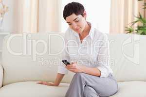 Charming brunette Woman sitting on a sofa with a phone