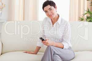 Smiling brunette Woman sitting on a sofa with a phone