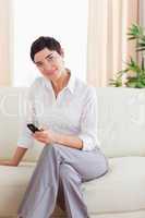 Brunette Woman sitting on a sofa with a phone