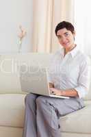 Cute Woman sitting on a sofa with a laptop