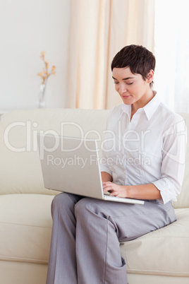 Charming Woman sitting on a sofa with a laptop