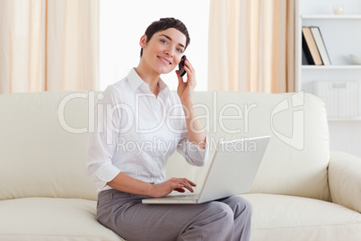 Gorgeous woman with a laptop and a phone looking into the camera
