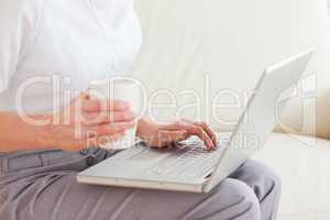Close up of a woman holding a cup having a notebook on her lap