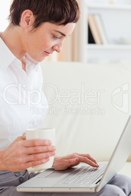 Close up of a woman with a cup having a notebook on her lap