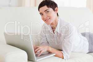Smiling Woman lying on a sofa with a laptop
