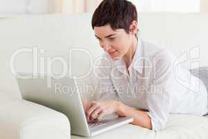 Woman lying on a sofa with a laptop