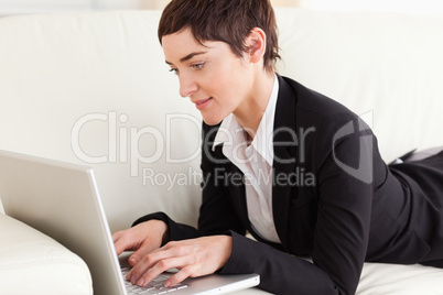Charming businesswoman lying on a sofa with a laptop