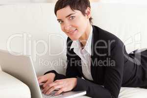 Businesswoman lying on a sofa with a laptop