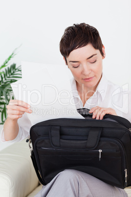 Brunette businesswoman putting some papers in her bag