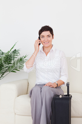 Short-haired woman on the phone with a suitcase