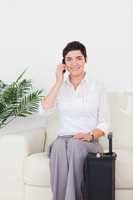 Short-haired woman on the phone with a suitcase