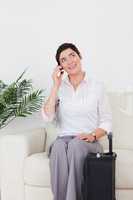 Short-haired woman on the phone with a suitcase