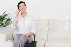 Short-haired smiling woman on the phone with a suitcase