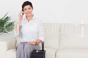 Short-haired charming woman on the phone with a suitcase