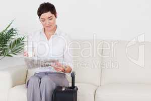 Short-haired charming woman with a suitcase, a newspaper and a c